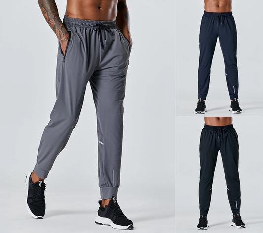 Gray and black jogger pants worn by a person on a white background